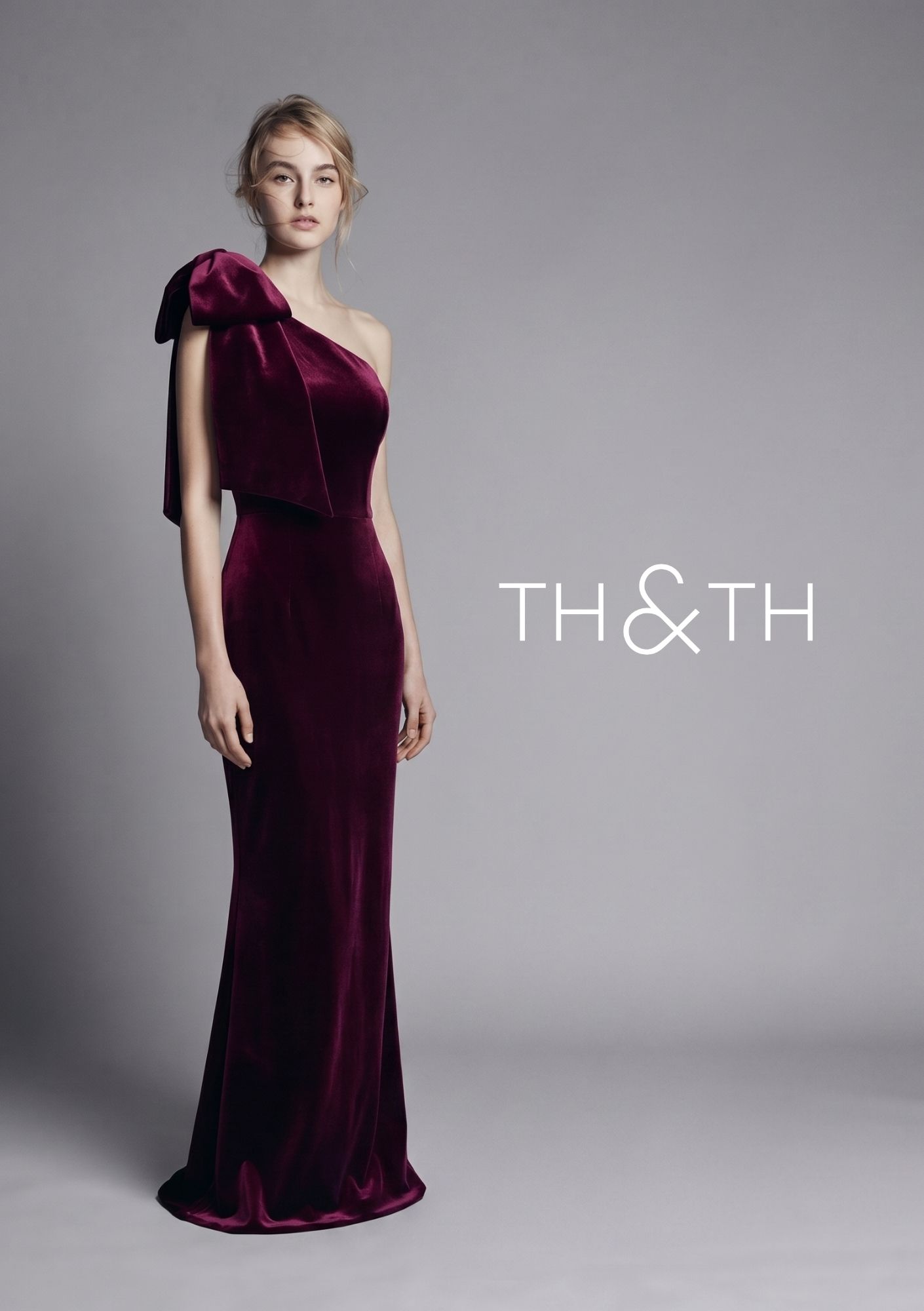 Model wearing a burgundy velvet one-shoulder Ritz evening gown by Kitty Dickerson-Firth